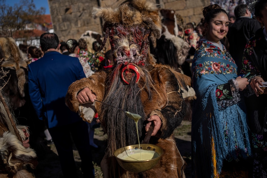 Un hombre vestido como un animal salvaje se para en una multitud de carnavales.