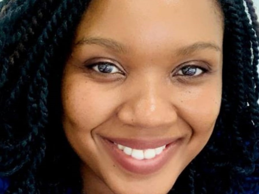 A woman smiling at the camera with a twisted hair braid.