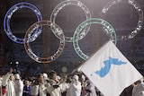Korean flag-bearer's Bora Lee and Jong-In Lee walk side by side holding blue and white flag under Olympic rings