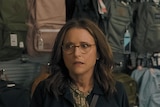 A middle-aged brunette white woman with glasses stands next to another middle-aged brunette woman in a store, looking perturbed.