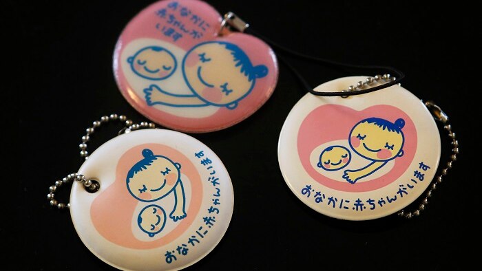 Cartoon drawing of mother and baby on round keychains, lying on a black background