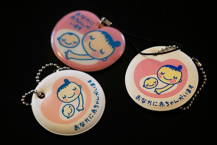 Cartoon drawing of mother and baby on round keychains, lying on a black background