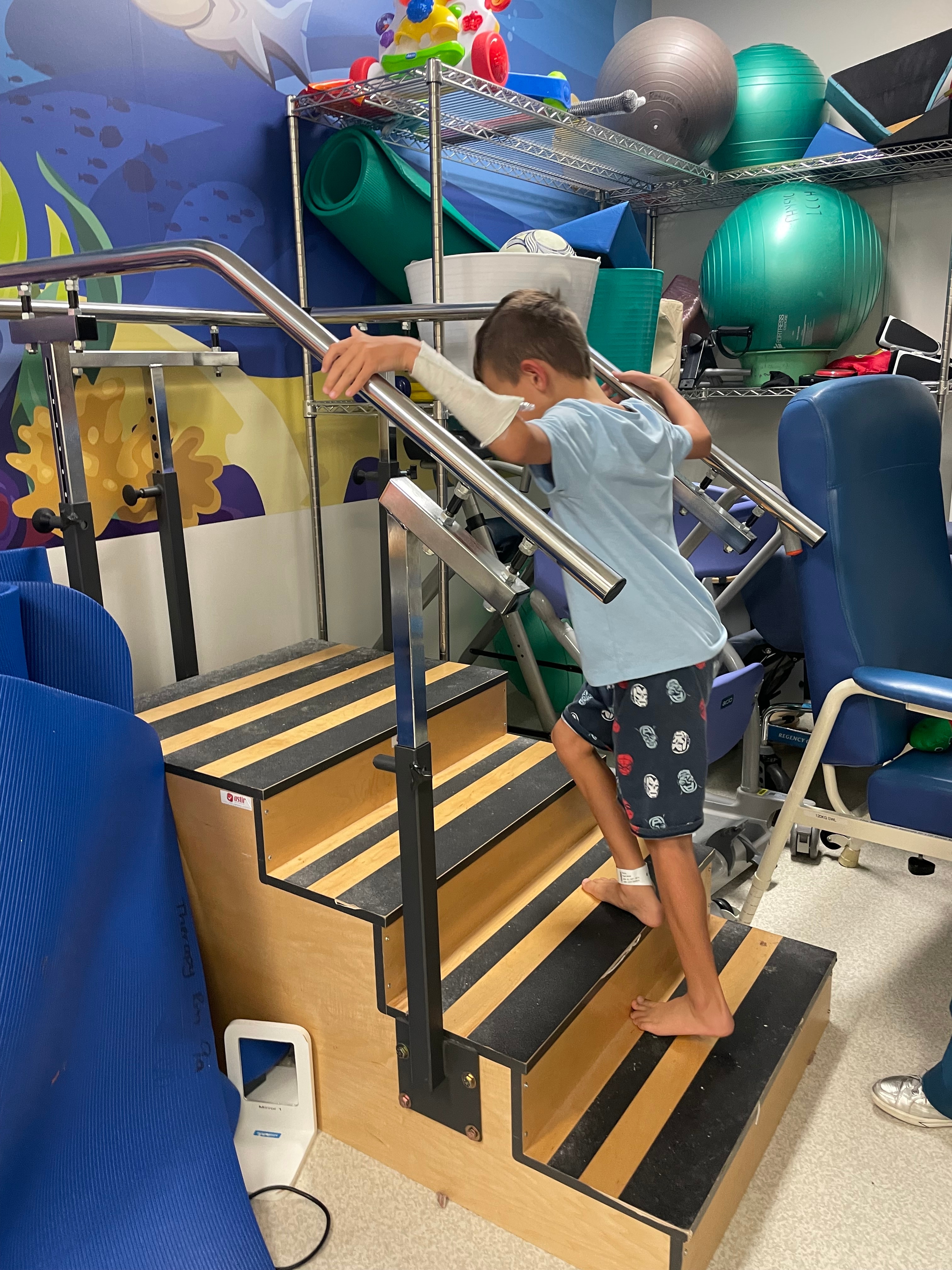 Hugh sube un tramo de escaleras en una sala de tratamiento de fisioterapia. 