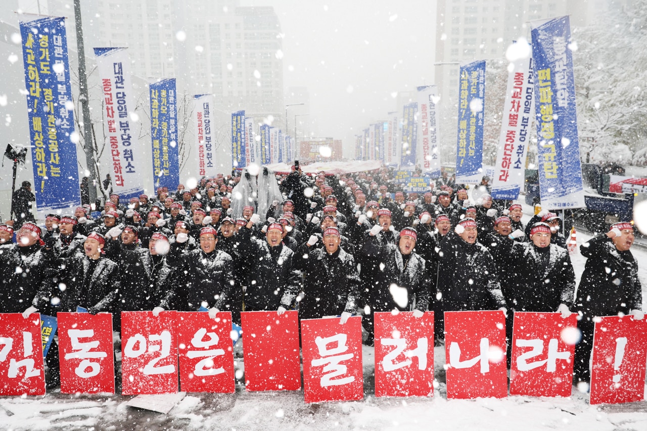 Multitudes sostienen carteles y protestan en un día de nieve. 