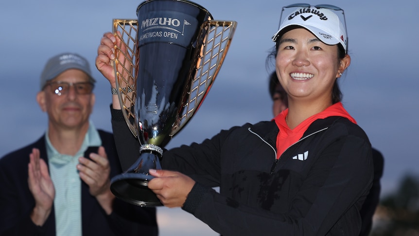 Rose Zhang smiles as she holds up a trophy
