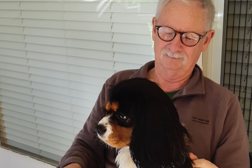 Rob Rogers sits with his dog Monty on his lap.