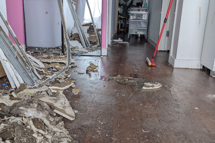 The inside of a storm-damaged shop, with debris on the ground and a mop.