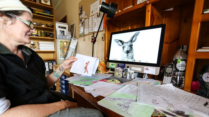 Nikki Medwell sitting at her desk looking at pictures drawn by children from around the world.