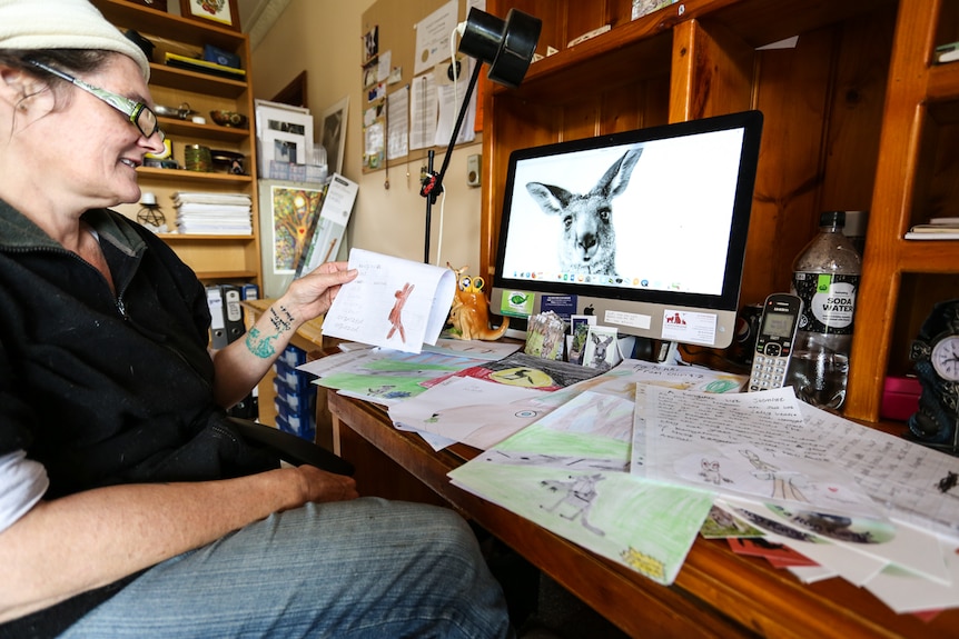 Nikki Medwell sitting at her desk looking at pictures drawn by children from around the world.