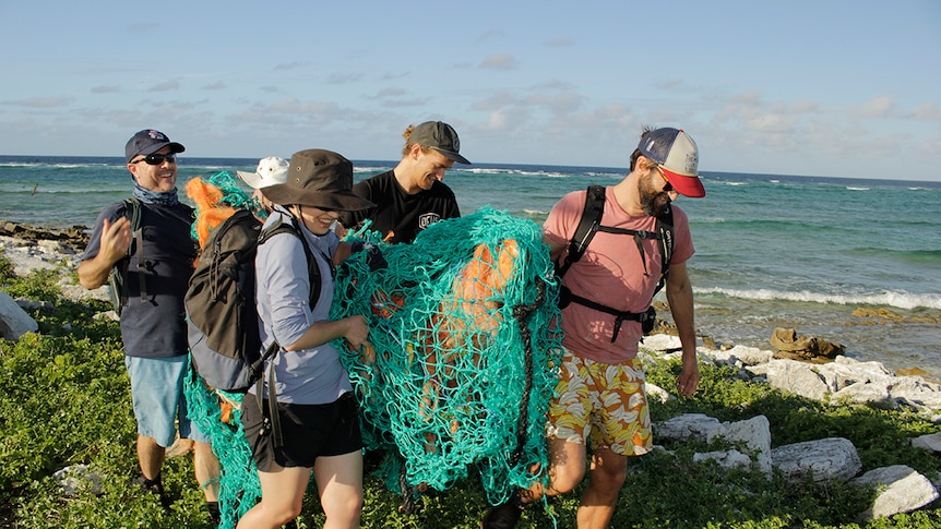 Volunteers work to remove a ghost net from a remote island in the Coral Sea Marine Park.