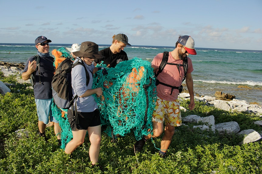 Volunteers work to remove a ghost net from a remote island in the Coral Sea Marine Park.