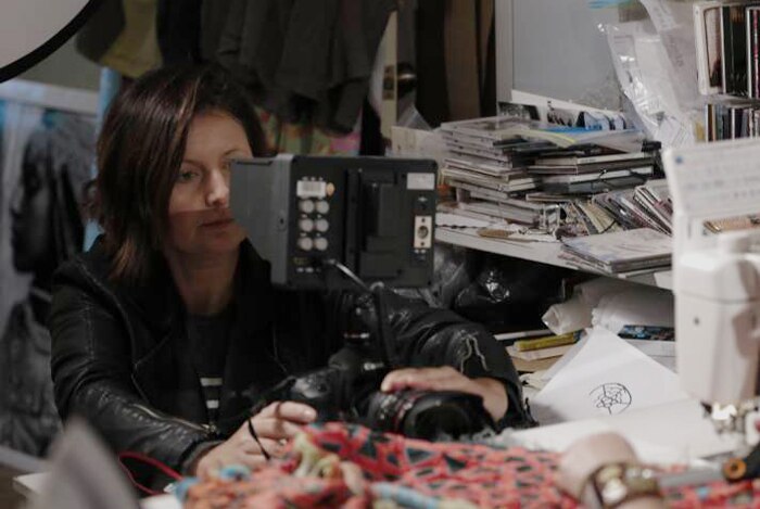 Portrait of Nicky Elliot filming a woman sitting at a sewing machine