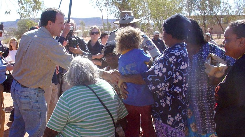Mal Brough shakes hands with a person as he visits the Santa Teresa community in the NT