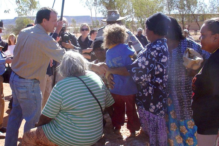 Mal Brough shakes hands with a person as he visits the Santa Teresa community in the NT