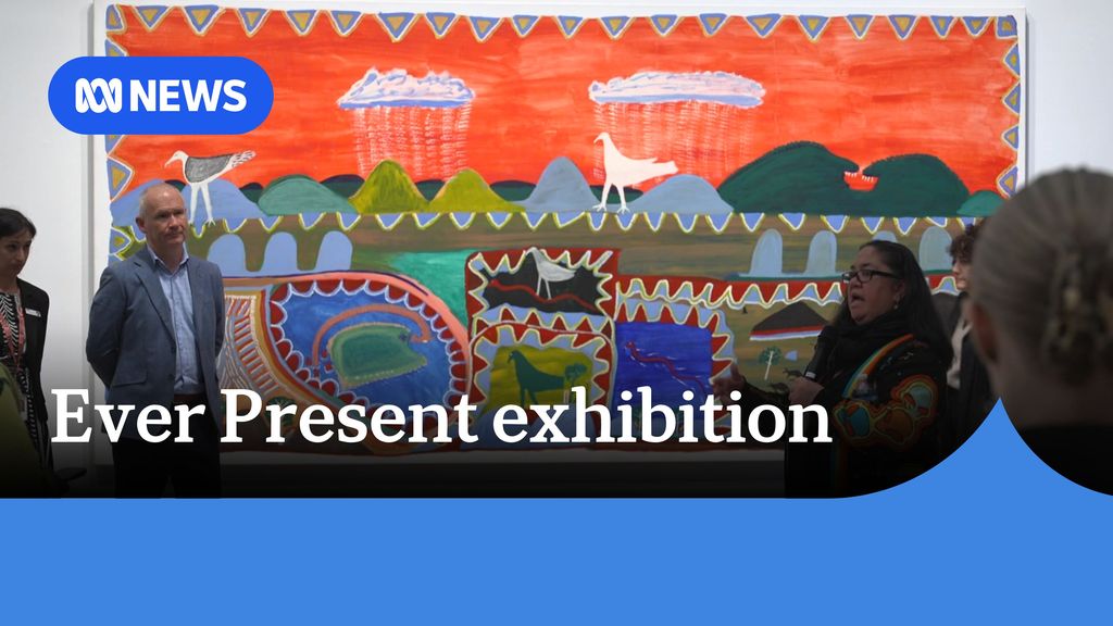 Ever Present exhibition: A woman speaks in front of a large artwork. People mingle, listening to her.