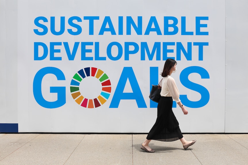 A women walks past a sign for the Sustainable Development Goals.