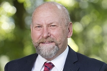 A bald man with a beard wearing a suit and tie