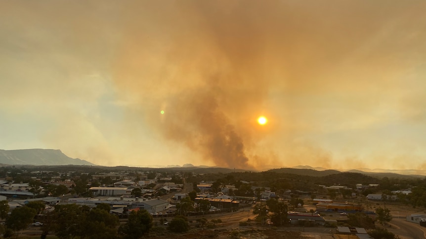 A red sun and a large amount of smoke can be seen beyond the Alice Springs skyline.
