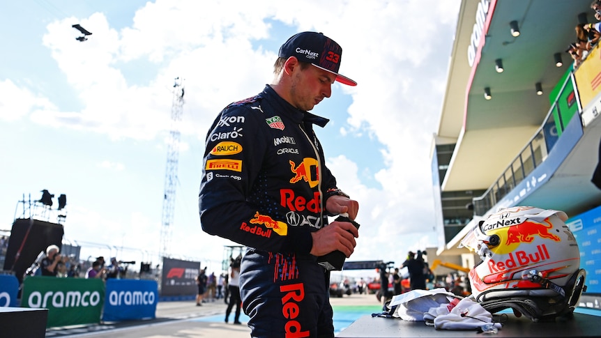 Max Verstappen looks serious as he walks on the track and opens a bottle