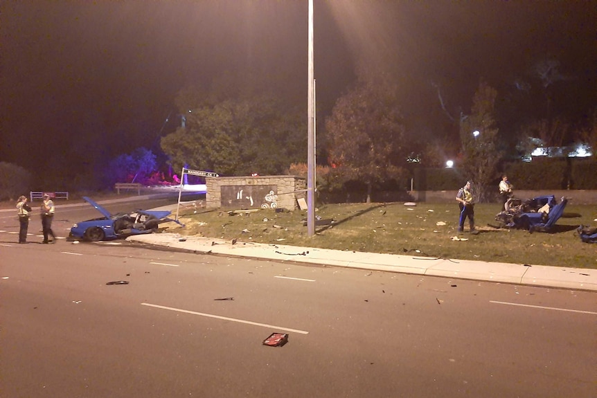 A pieces of a car are strewn across a road and area of grass.