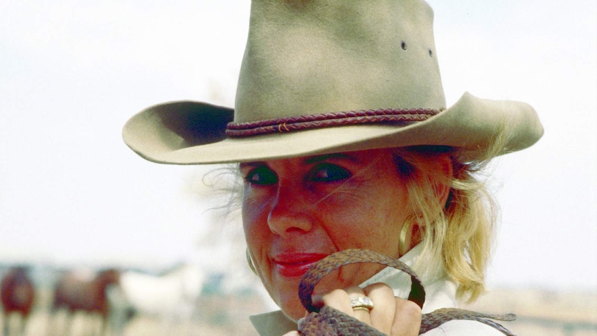 Sally Warriner with hat and whip with cattle in background