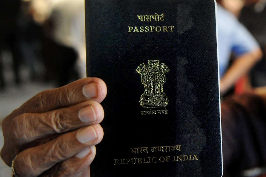 An Indian woman holds up her passport.