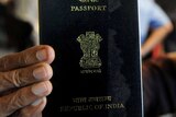 An Indian woman holds up her passport.