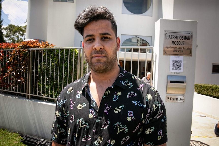 A man poses for a photo outside a mosque