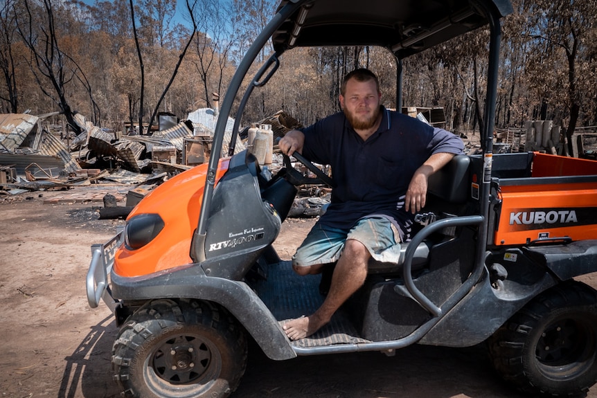 23-year-old man sitting on the seat in a quad bike parked in front of a house burnt to the ground.