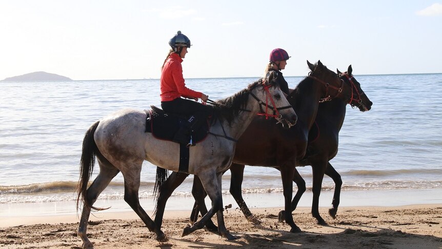Two women riding horses at the beach