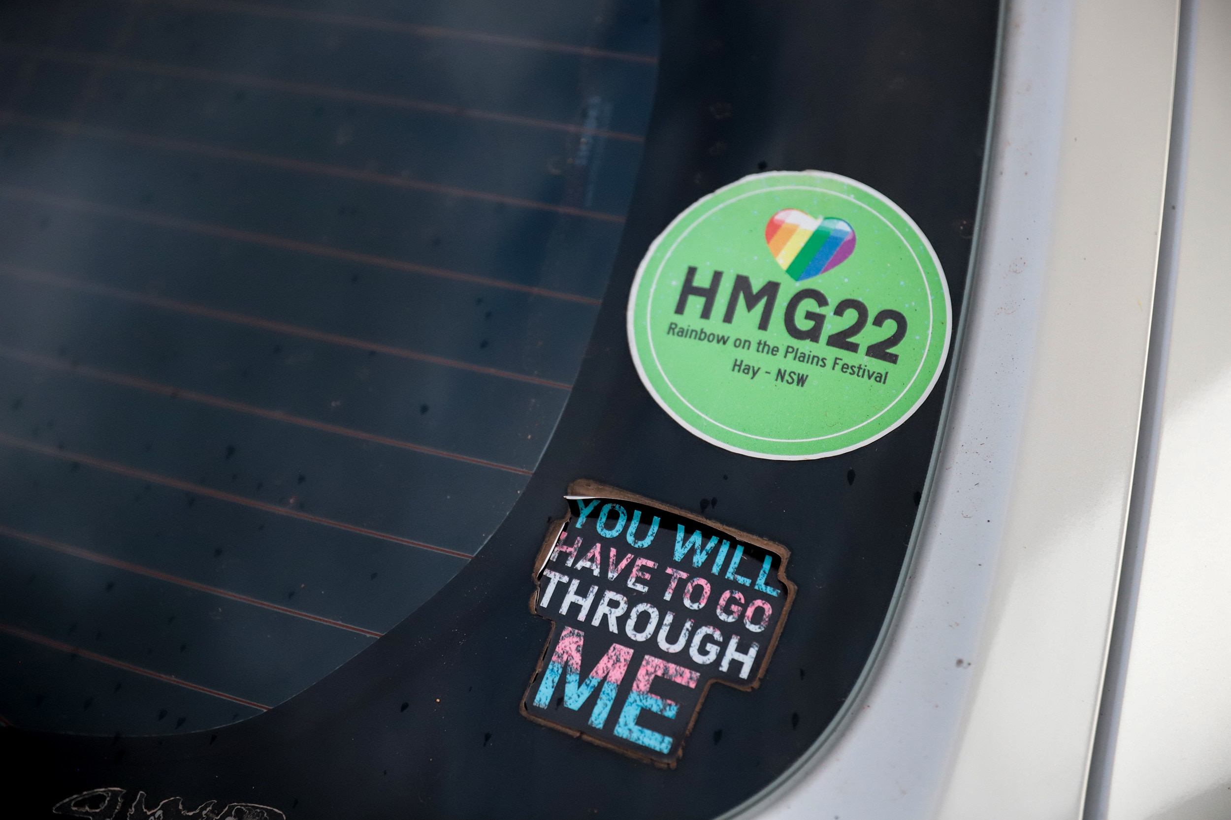 Stickers on the back windscreen of a white hatchback expressing support for LGBTIQ+ rights