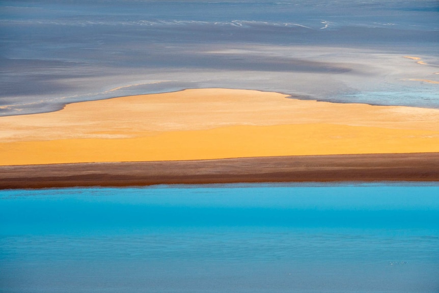The pastel colours of Lake Eyre form thick layers of bright blues and oranges.