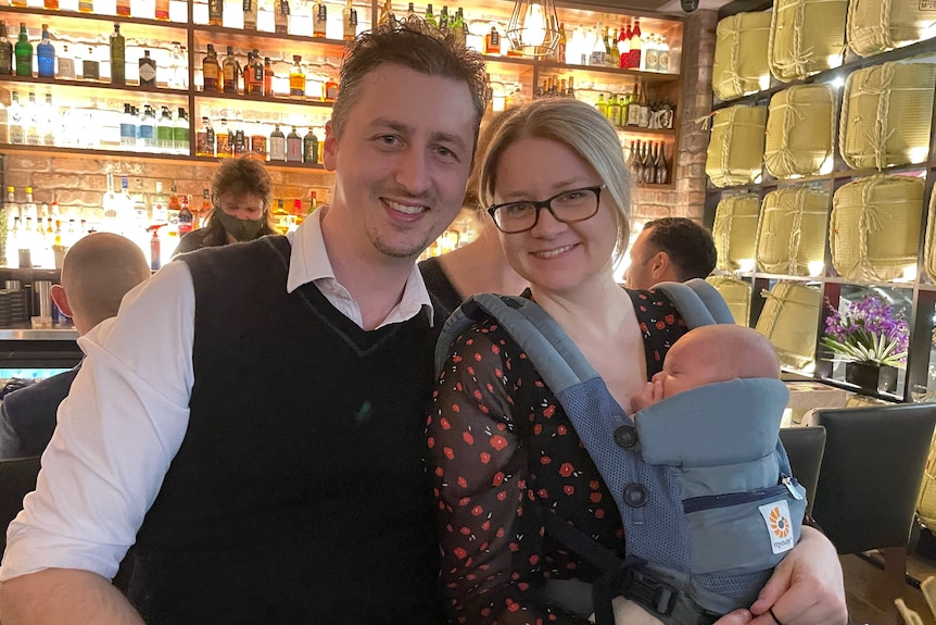 Ken Simpson and Katherine Goodall sit in a restaurant while holding baby Mackenzie