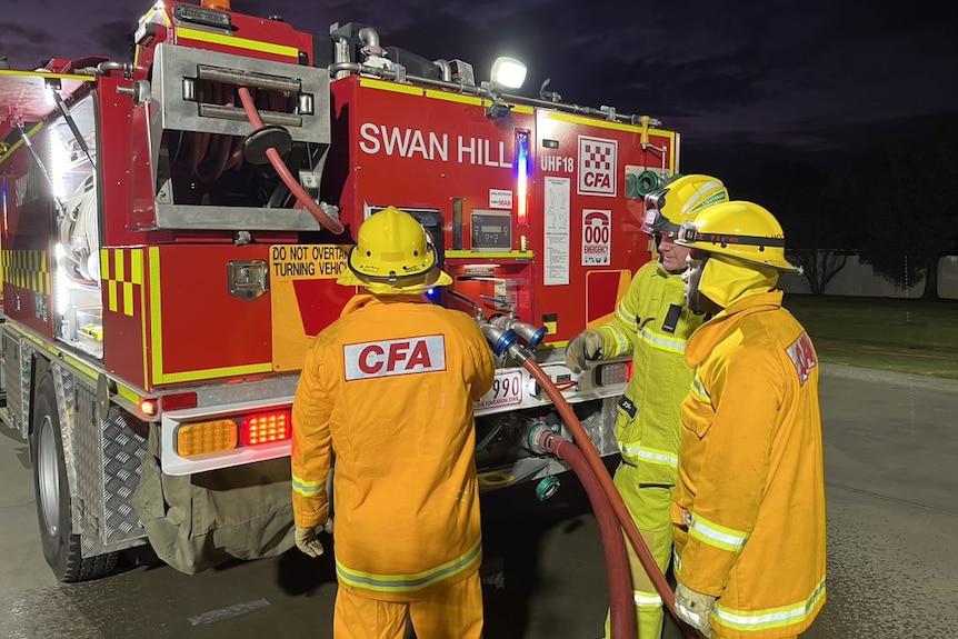 Men dressed in CFA uniforms looking at a fire truck.