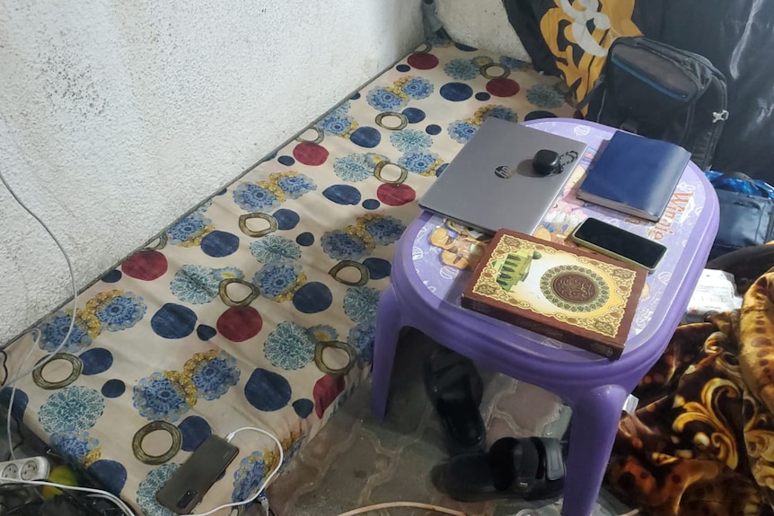A place showing a mattress, table, and laptop in a small space in Gaza.