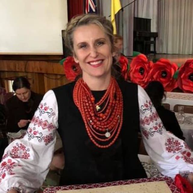 A woman wearing traditional Ukrainian attire smiles for a photo