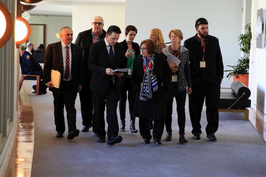 Nick Xenophon walks family members of Oakden nursing home residents along corridor.