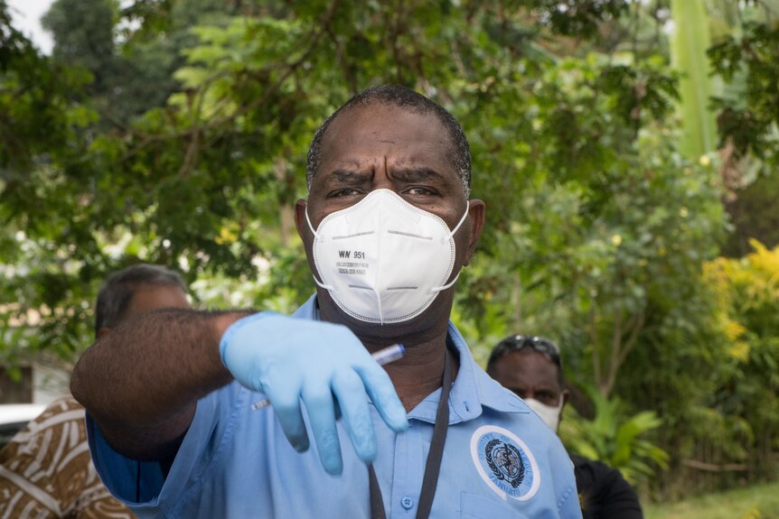 A Vanuatu health official gestures while wearing a mask.