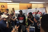 Protesters yell and stand in front of posters at the mayors press conference