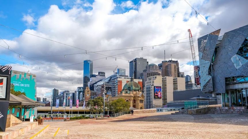 A virtually empty Federation Square under a sunny sky dotted with clouds.