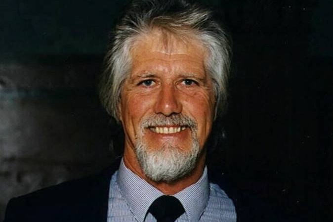 A headshot of a man with graying hair who is smiling at the camera
