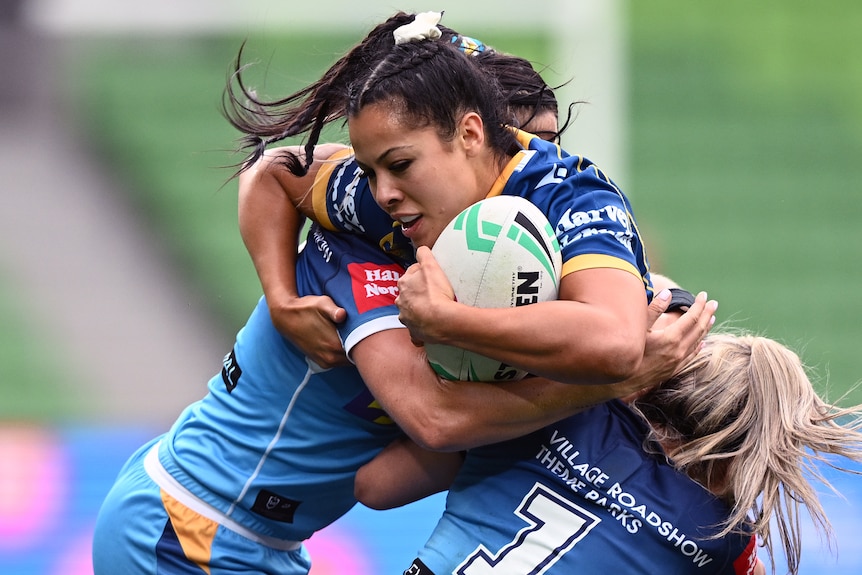 NRLW Eels player Tiana Penitani holds the ball and tries to break out of a two person tackle