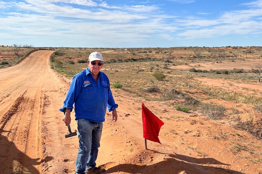 Un homme plante un drapeau dans l'outback