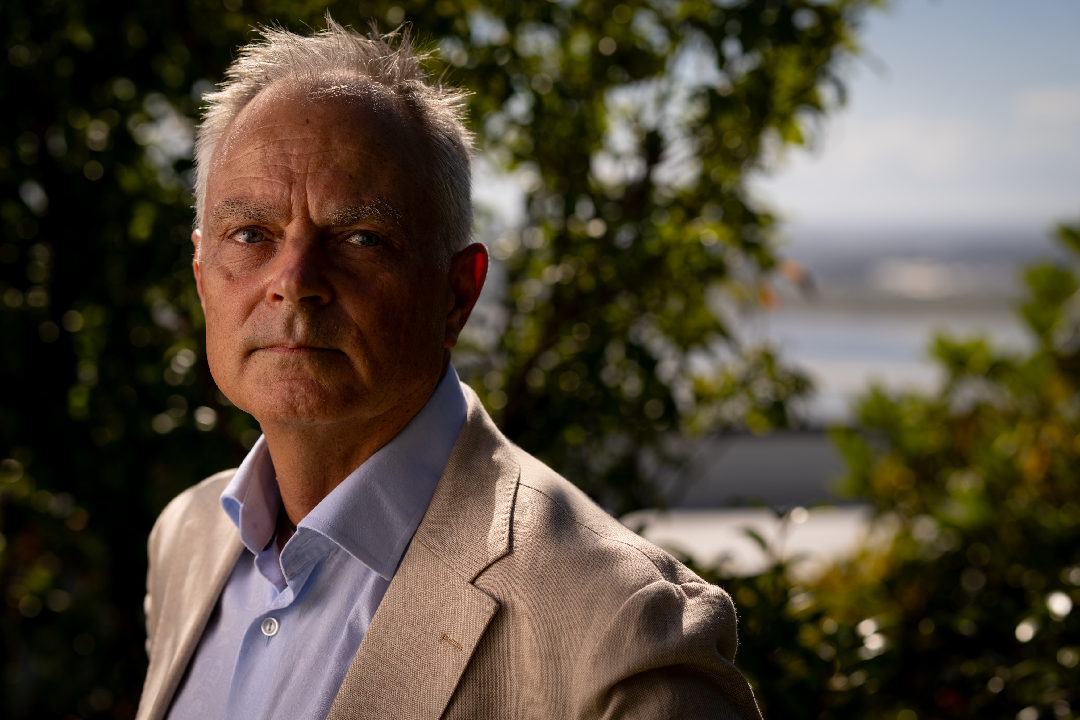 Un hombre con un traje color crema mira a la cámara