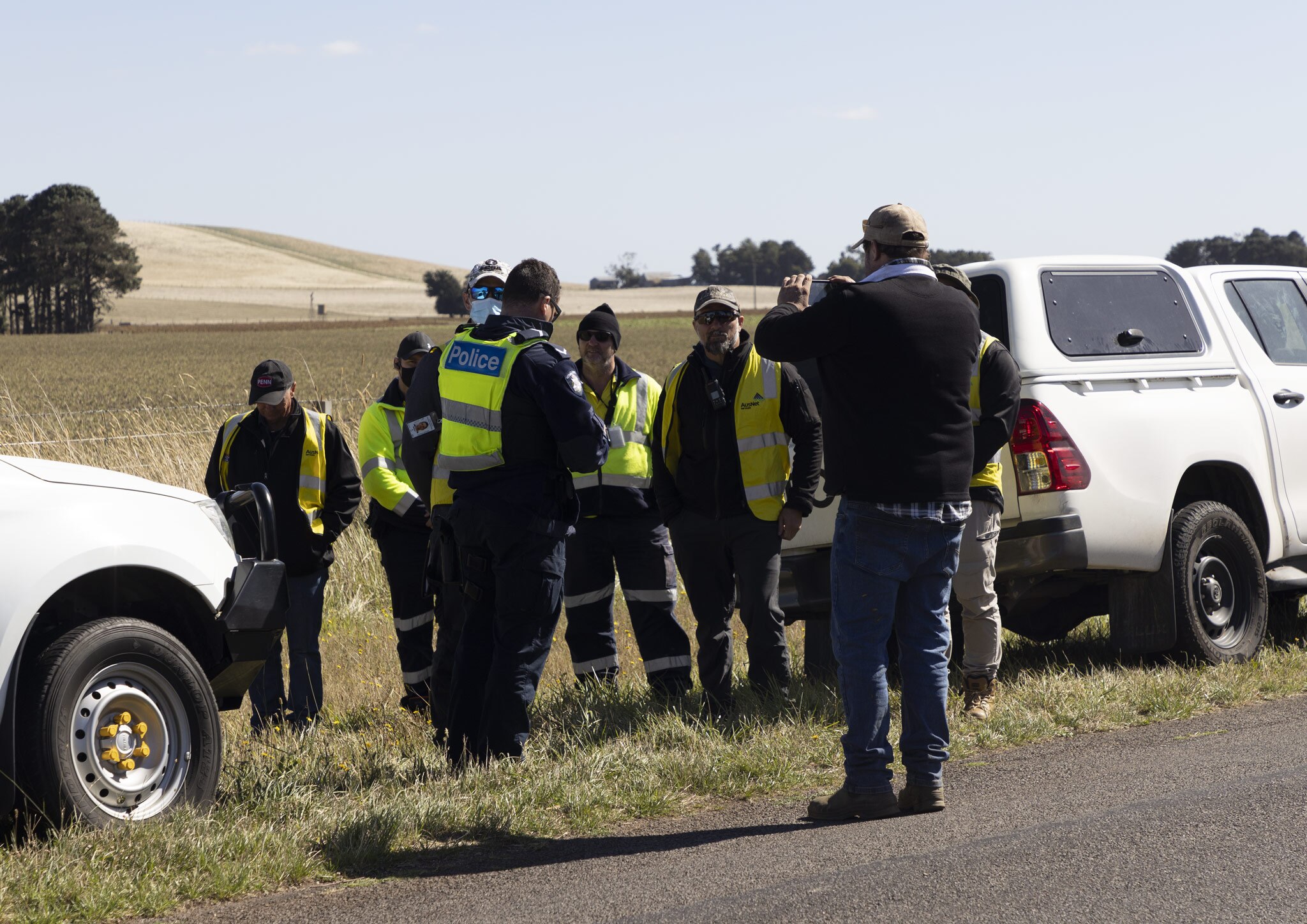 A group of police and contractors on a country road.