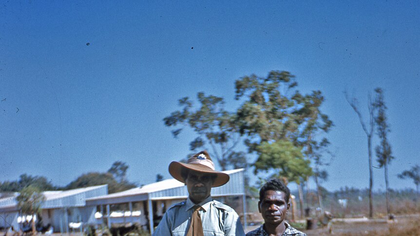 A photo of two well-dressed police trackers standing in a dusty field in the Northern Territory in the 1950s.