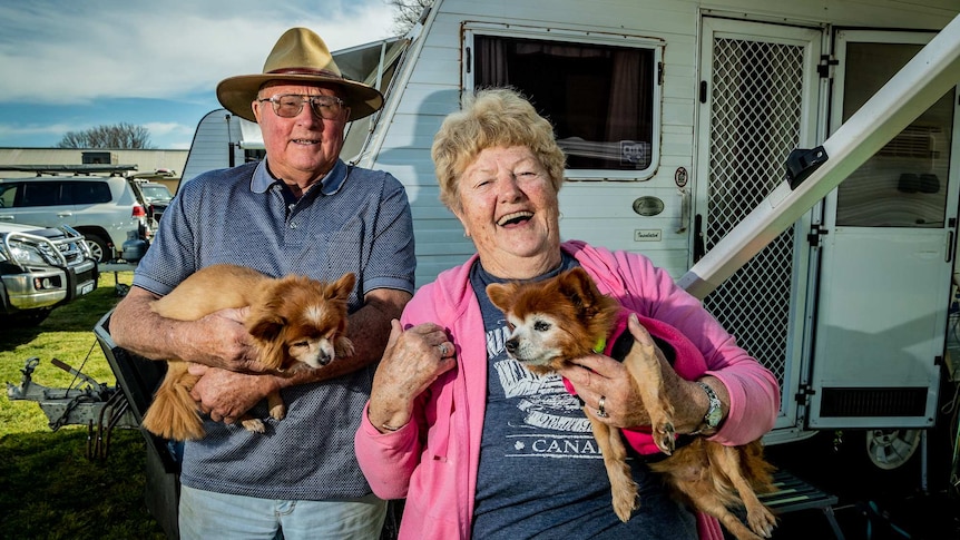 An older man and older woman outside a caravan