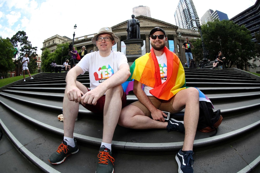 Men sit with yes flags in Melbourne.