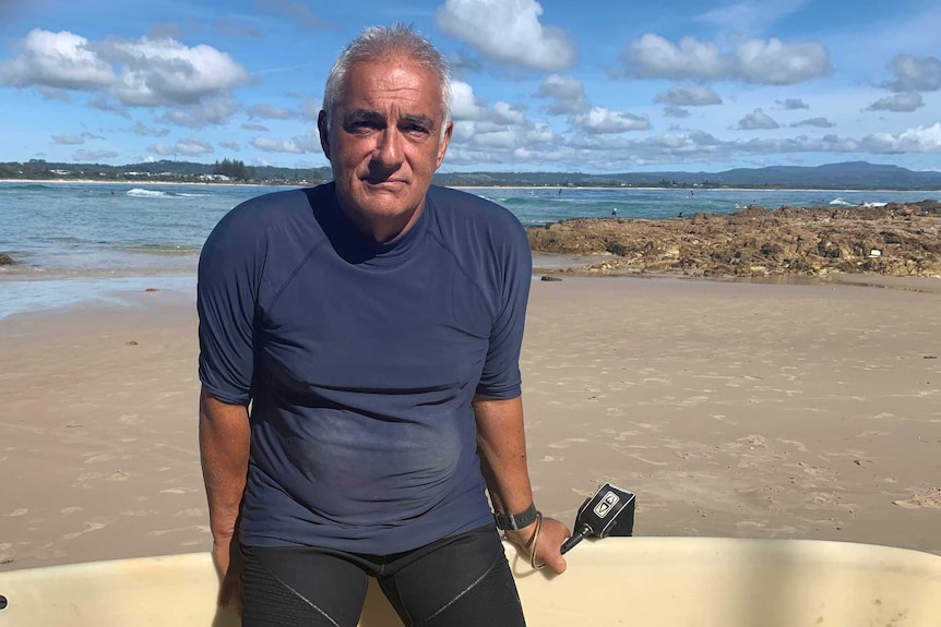 Byron Bay man Theo Papoulias with his surfboard at The Pass.