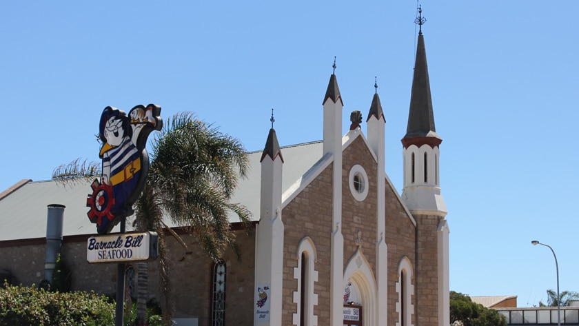 A former stone church with Barnacle Bills and other fish and chips signage out the front.